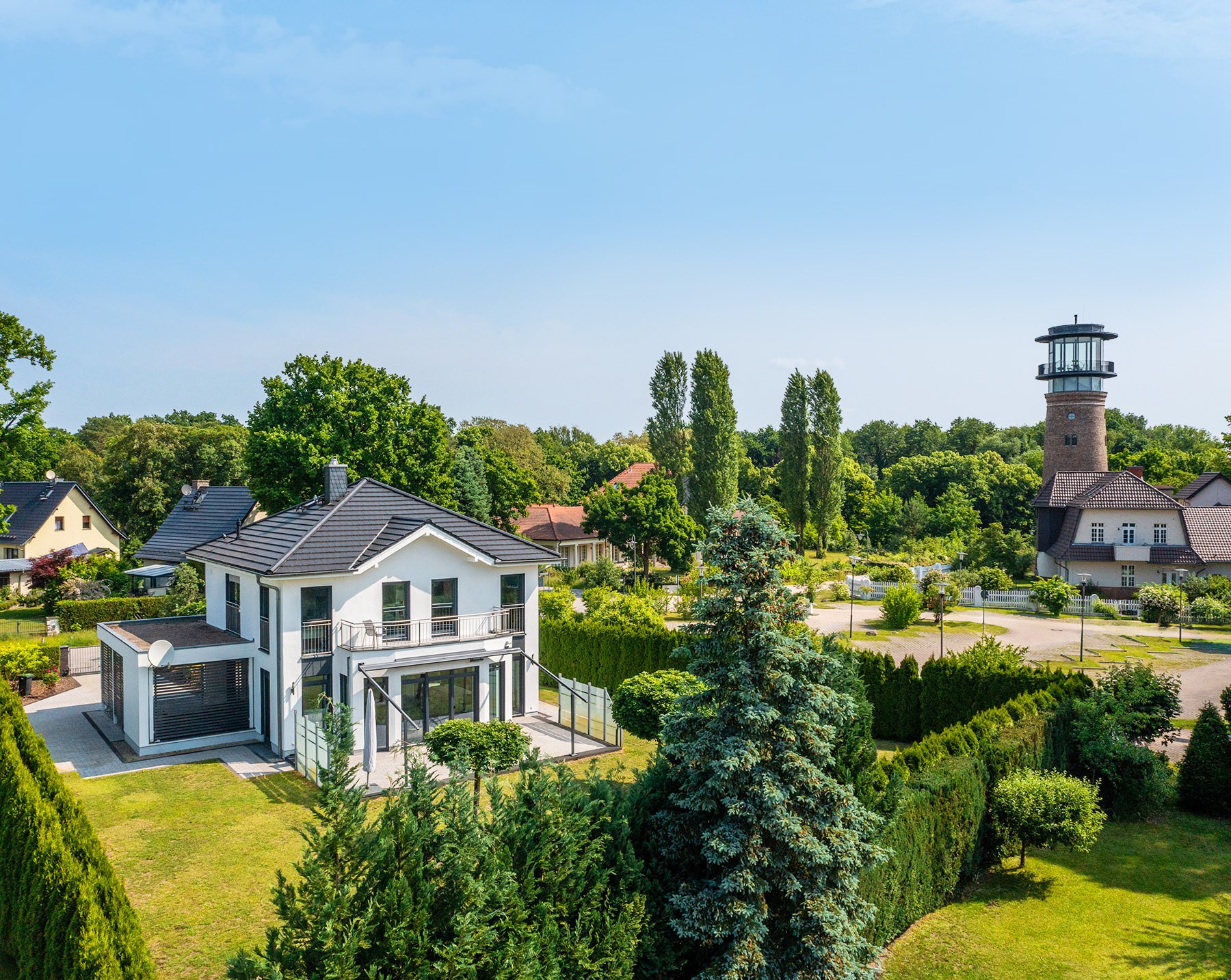 Luftaufnahme einer modernen Villa mit Garten und einem Turm in grüner Umgebung
