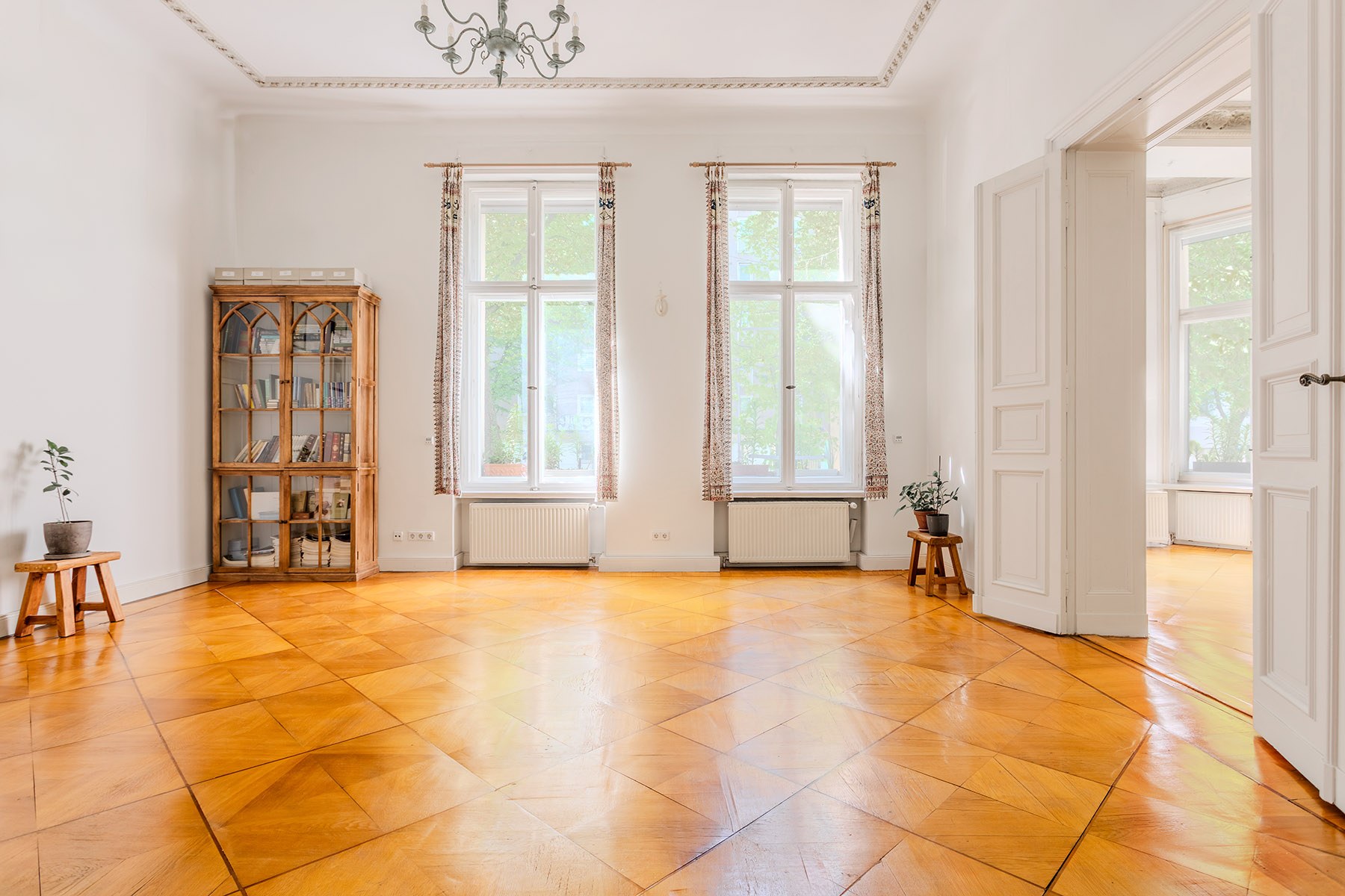 Großzügiger Wohnraum mit warmem Holzboden und großen Fenstern